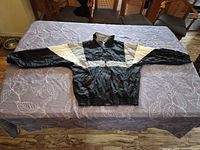 Front view of black, gray and white Starter Chicago White Sox windbreaker laid flat on table