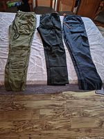 Three pairs pants laid flat on bed