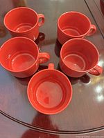 Five orange ceramic soup cups displayed top view