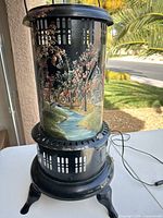 Full view of lamp showing painted cylinder scene and footed base