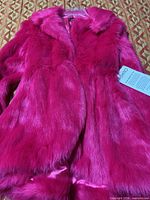 Front view of hot pink faux fur coat with tag attached