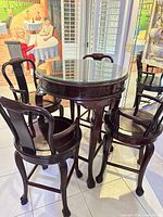 Bar-height table with glass top and four matching swivel stools