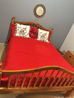 Wood spindle bed with red comforter and throw pillows