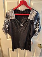 Front view of black jacquard blouse on hanger