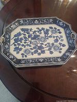 top view of blue and white porcelain serving tray showing floral pattern, border, and handles