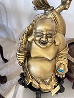 Full view of gold Buddha statue on carved black stand