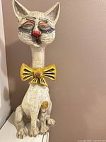 Front view of tall painted cat statue with yellow bow