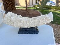 Left side view of carved resin tusk on black stand