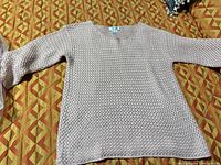 Front view of light pink knit sweater laid flat