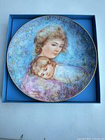 Front view of Edna Hibel collector plate in box