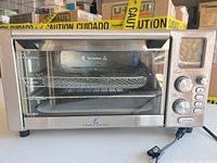 Front view of Emeril Lagasse AFO-001 air fryer oven showing stainless exterior and interior baskets