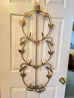 Full view of gold-tone metal wall hook rack hanging on door