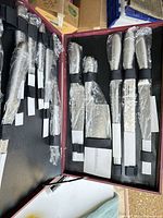 Open burgundy case showing knives in plastic sleeves and guards