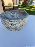 Full view of gray speckled granite mortar bowl on white surface