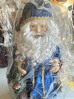 Front view of blue Father Christmas figure wrapped in plastic showing robe, beard, wreath