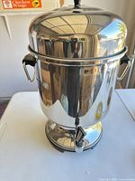 Front view of stainless steel electric urn showing spigot and base