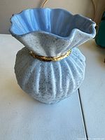 Front view of light blue ribbed ceramic vase with fluted rim and gold band