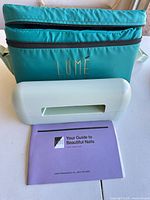 Teal Lumé carry bag, mint green nail lamp, purple manual