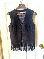 Front view of black suede fringe vest on hanger showing overall condition and fringe hem