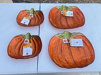 Four pumpkin-shaped orange glass plates on table