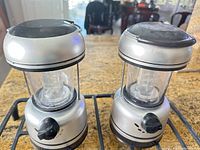Front view of the two identical silver and black battery lanterns