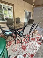 Complete patio dining set showing glass table and six chairs with cushions