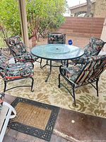 Round glass patio table with five matching chairs