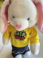 Full view of stuffed bunny in sweatshirt, jeans, shoes