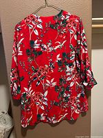 Full back view of red floral blouse on hanger