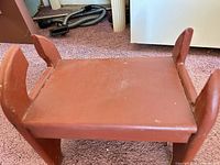 Top view of red wooden footstool showing platform and side supports