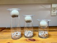 Front view of three glass vases showing candles and shell filler