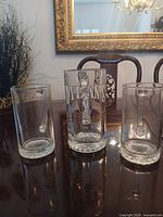 Front view of three Dylan's printed glass beer mugs showing graphics and size difference