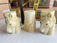 Three carved yellow wax candles with animal motifs