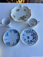 Group of five porcelain saucers showing variety of blue and multicolor floral patterns and gold trim