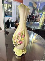 Full view of cream ceramic floral vase with pale green foot, flared rim and gold trim