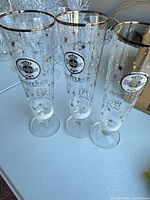 Three Warsteiner pilsner glasses standing side by side