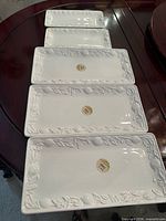 Stack of four rectangular platters showing embossed borders and stickers