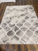 Full view of 5' x 8' beige gray ivory Moroccan trellis rug on wood floor