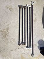 Six bronze adjustable curtain rods with two finial styles displayed on ground