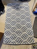 Full view of blue runner rug with off-white wave pattern on concrete floor