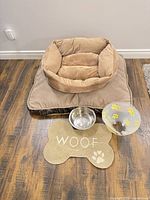 Overall view of dog bed on pad with bowl, mat and cone
