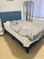 Full-size blue upholstered bed showing headboard, frame, side rails, mattress and legs