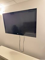 Front view of LG flat screen TV mounted on wall with power cord visible