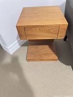 Front view of light brown veneer nightstand showing drawer and base