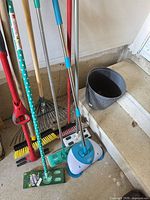 Group of long-handle cleaning tools leaning against wall