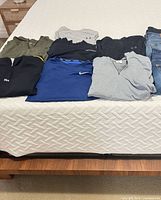 Eight folded garments on bed