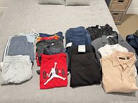 All folded garments laid out on bed showing variety and quantity