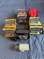 Group shot of espresso machine, case, pouch and six visible capsule boxes