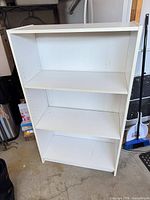 Front view of white bookcase showing three shelves and top tier