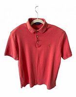 Front view of salmon polo on hanger showing logo and buttons